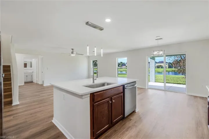 Kitchen with pendant lighting, light wood-type flooring, ceiling fan with notable chandelier, an island with sink, and dishwasher