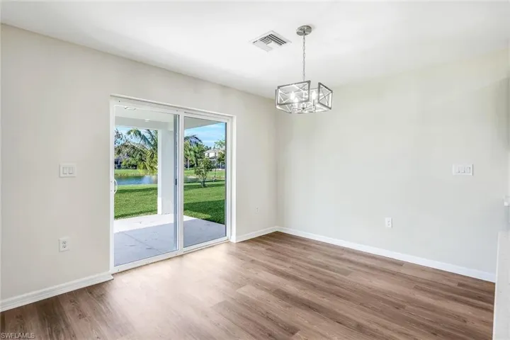 Unfurnished room with an inviting chandelier, a wealth of natural light, and hardwood / wood-style flooring