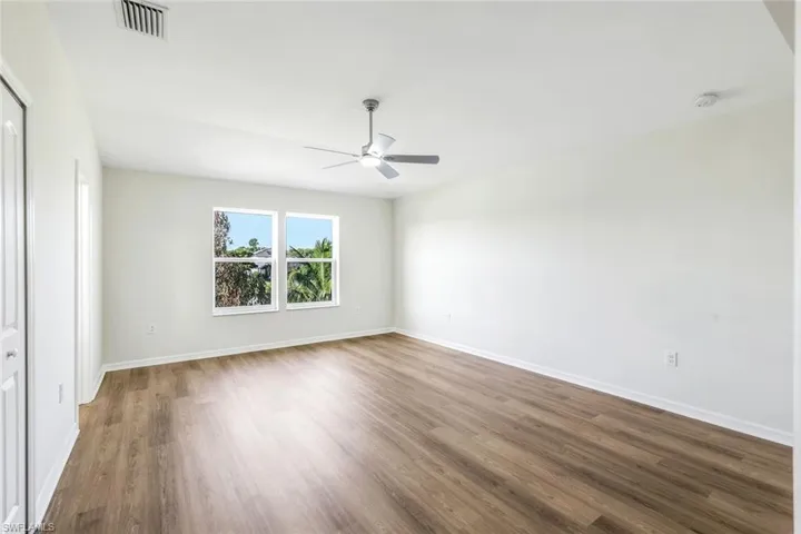 Empty room featuring dark wood-type flooring and ceiling fan