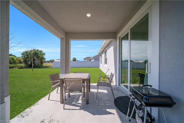 Covered patio with a concrete slab, recessed lighting, and direct access to the expansive green lawn via sliding glass doors