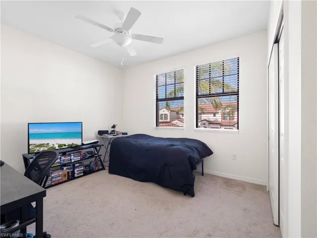 Bedroom with carpet, ceiling fan, a desk, and a closet