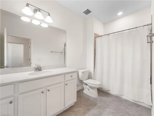 Bathroom with curtained shower, vanity, and light tile patterned floors