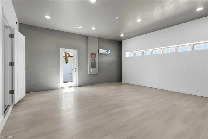 Empty room with recessed lighting, light wood finished floors, a textured wall, and electric panel