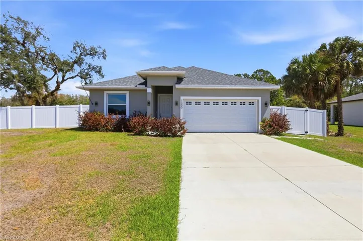 View of front facade with a garage, a shingled roof, driveway, and stucco siding