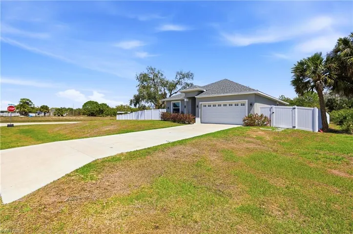 Ranch-style house featuring a gate, concrete driveway, an attached garage, a shingled roof, and stucco siding