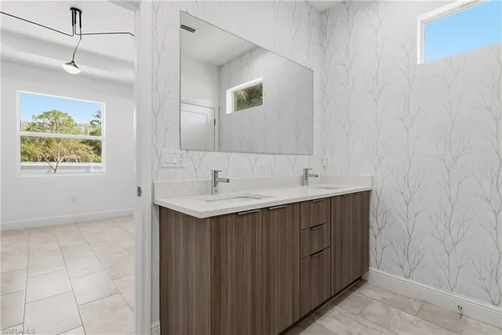 Bathroom with wallpapered walls and double vanity