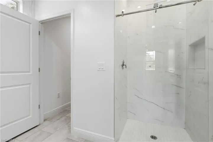 Master bathroom with a marble finish shower and baseboards