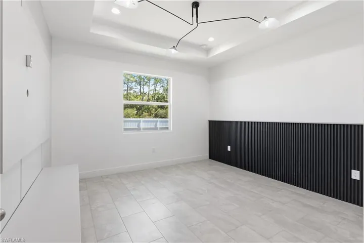 Master bedroom with suspended lighting and a tray ceiling