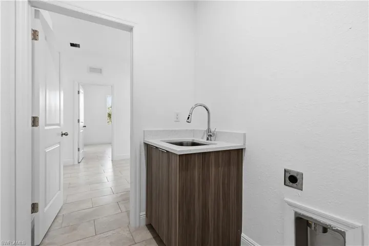 Laundry area with light tile patterned floors, a textured wall, and electric dryer hookup