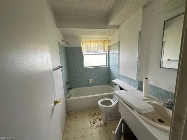 Full bathroom featuring vanity, a textured ceiling, shower / bath combination, and tile patterned floors