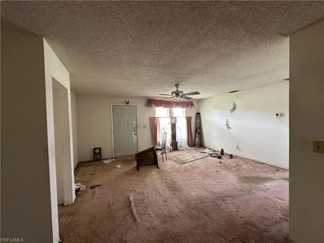 Unfurnished living room featuring a textured ceiling, carpet flooring, and ceiling fan