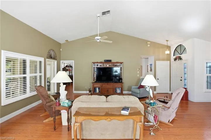 Living area featuring a high ceiling, light wood finished floors, and a ceiling fan