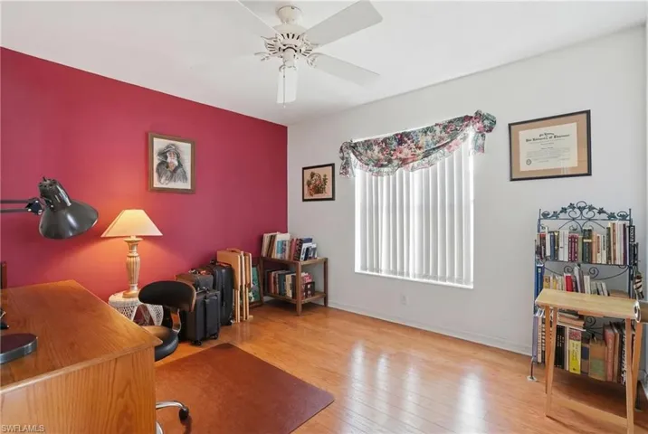 Home office featuring light wood finished floors, a ceiling fan, and an accent wall