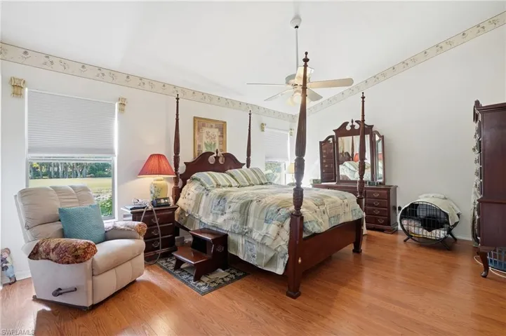 Bedroom with light wood finished floors, lofted ceiling, and a ceiling fan