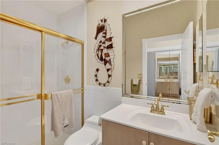 Bathroom with a shower stall, vanity, and tile walls