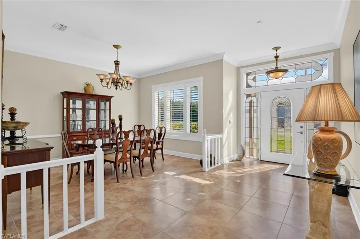 Entrance foyer with ornamental molding, tile patterned floors, and a chandelier