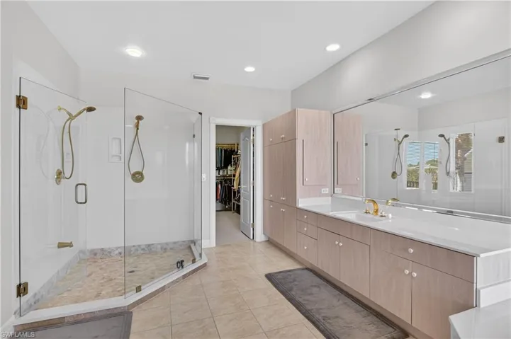 Bathroom featuring a stall shower, a walk in closet, vanity, light tile patterned floors, and recessed lighting