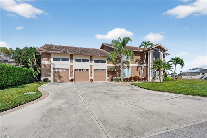 View of front facade featuring a front yard, driveway, a tiled roof, stucco siding, and a garage