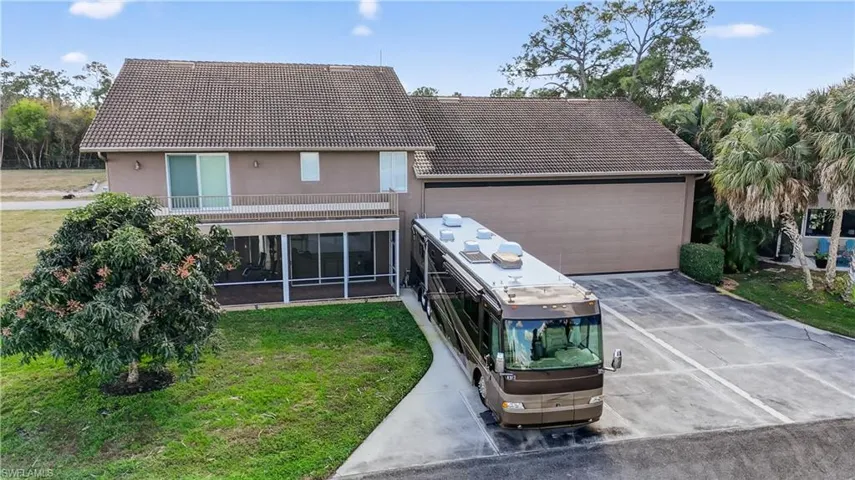 View of front of house featuring a tile roof, a front lawn, a sunroom, and stucco siding