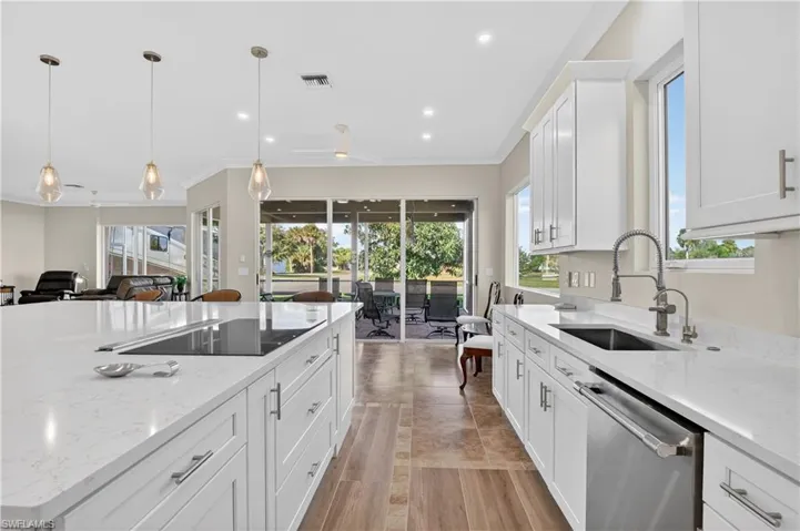 Kitchen with white cabinets, light stone countertops, stainless steel dishwasher, pendant lighting, and open floor plan