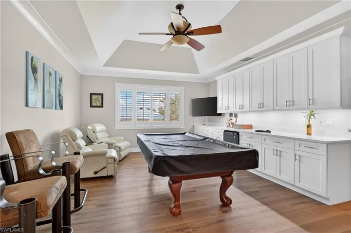 Rec room with light wood-style flooring, a ceiling fan, a tray ceiling, billiards, and crown molding