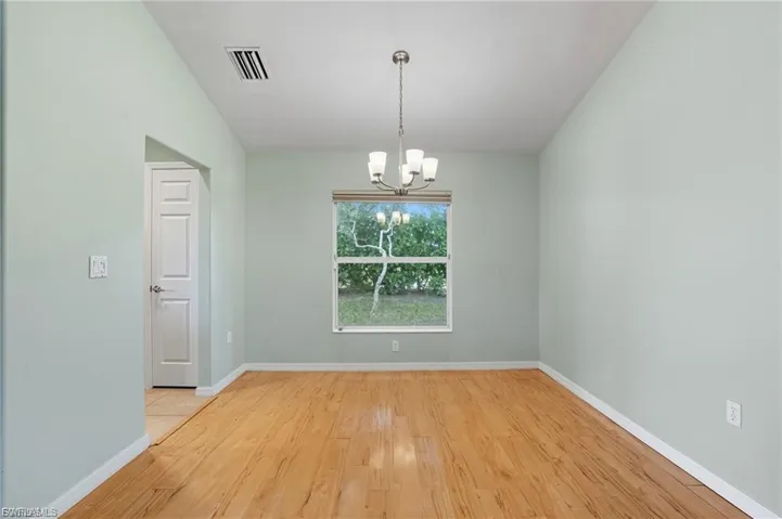 Empty room with hanging lights and light wood finished floors