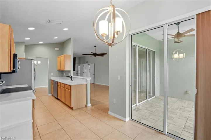 Kitchen with a chandelier, a ceiling fan, light tile patterned floors, stainless steel appliances, and light wood finish cabinets