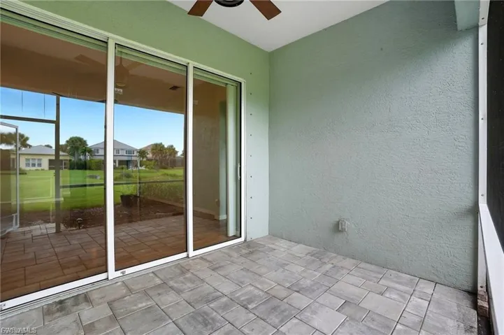 Unfurnished sunroom with ceiling fan, a residential view, and a patio