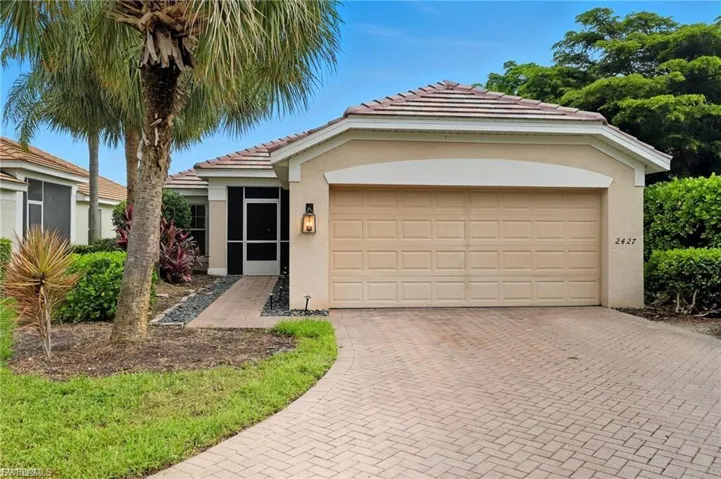 View of front facade featuring an attached garage, decorative driveway, stucco siding, a tiled roof, and a sunroom