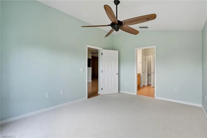 Unfurnished bedroom with light carpet, lofted ceiling, a ceiling fan, and ensuite bathroom
