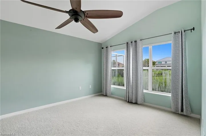 Unfurnished room featuring vaulted ceiling, light colored carpet, and a ceiling fan