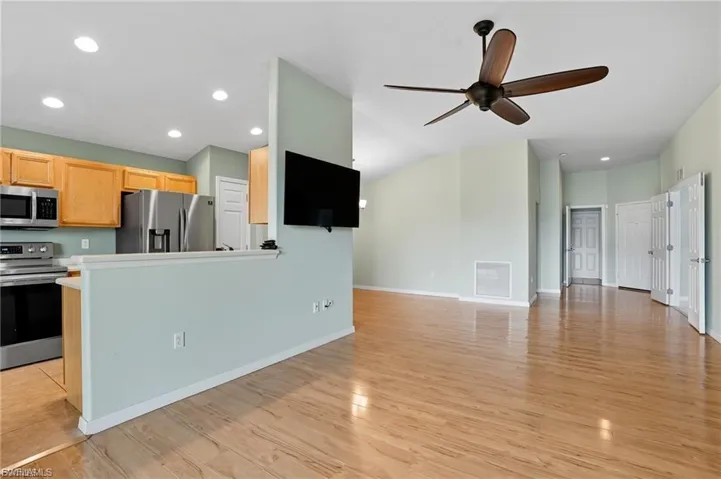 Kitchen with stainless steel appliances, light wood finish cabinets, light countertops, recessed lighting, and open floor plan