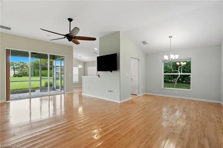 Unfurnished living room with suspended lighting, lofted ceiling, a ceiling fan, and light wood-style flooring