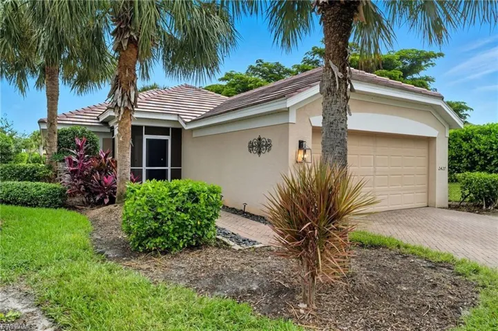 Ranch-style house with a garage, decorative driveway, a tiled roof, stucco siding, and a sunroom