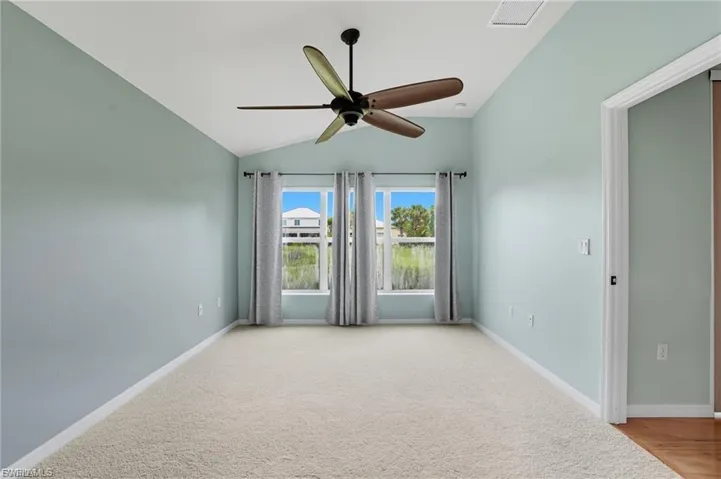 Unfurnished room with ceiling fan, light colored carpet, and lofted ceiling
