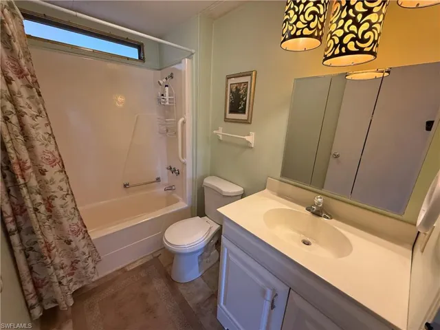 Bathroom with shower / bath combination with curtain and vanity
