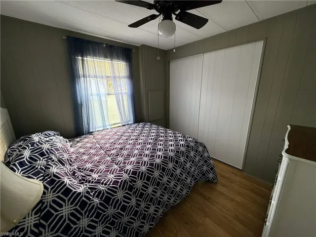 Bedroom with wood finished floors, wooden walls, and a ceiling fan