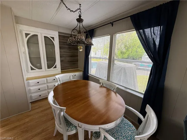 Dining area with wood walls, light wood-style flooring, and a chandelier