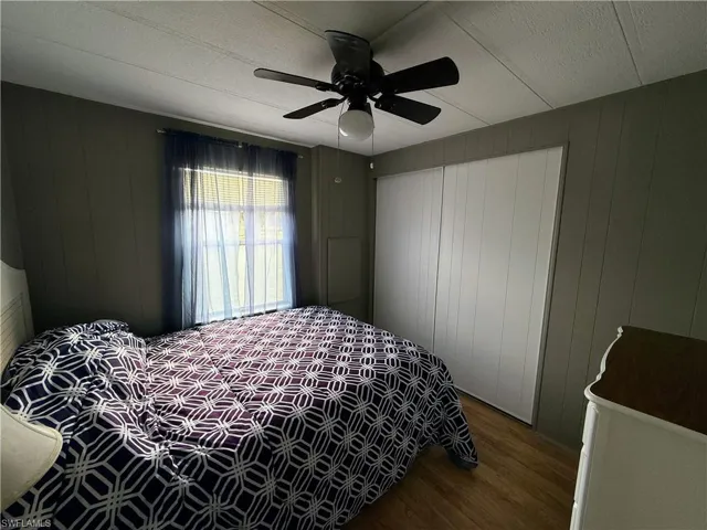Bedroom featuring wood finished floors, wooden walls, and ceiling fan