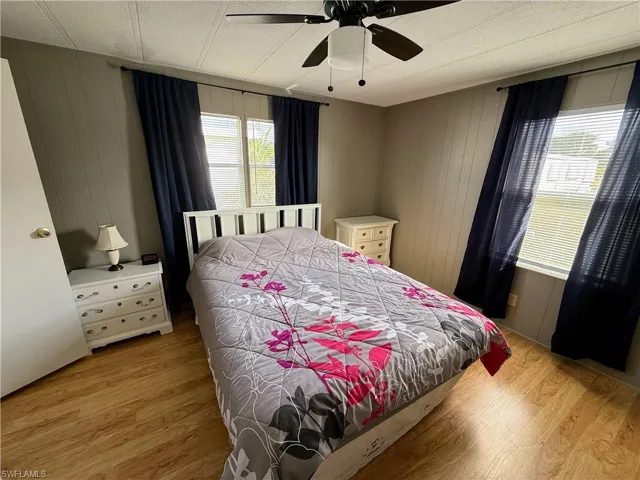Bedroom featuring light wood-style flooring, ceiling fan, and wooden walls