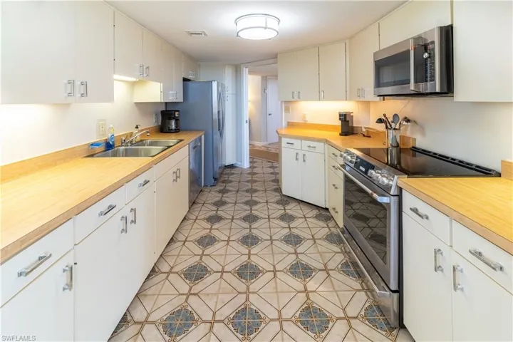 Kitchen with white cabinets, appliances with stainless steel finishes, and sink