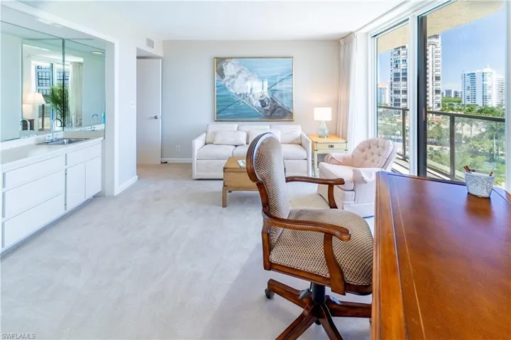 Living room featuring a wealth of natural light, light colored carpet, and sink