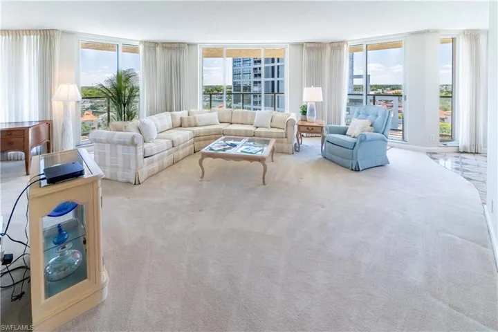 Carpeted living room with a wall of windows and a healthy amount of sunlight
