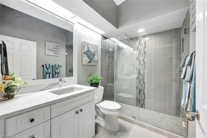 Bathroom featuring tile patterned flooring, vanity, toilet, and an enclosed shower