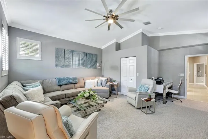 Carpeted living room with ornamental molding, ceiling fan, and lofted ceiling