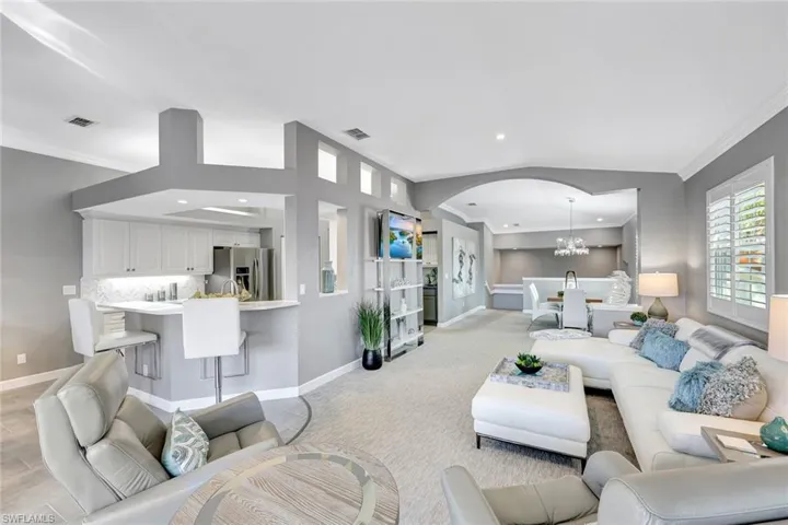 Living room featuring light hardwood / wood-style flooring, a chandelier, lofted ceiling, and ornamental molding