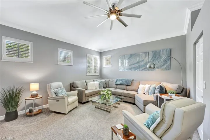 Living room featuring light colored carpet, ceiling fan, and crown molding
