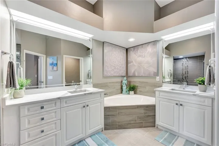 Bathroom featuring tile patterned flooring, vanity, and tiled bath