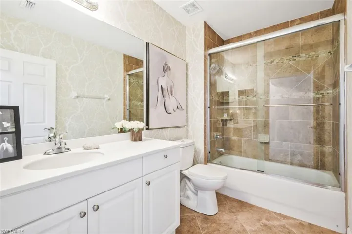 Bathroom with vanity, enclosed tub / shower combo, and wallpapered walls