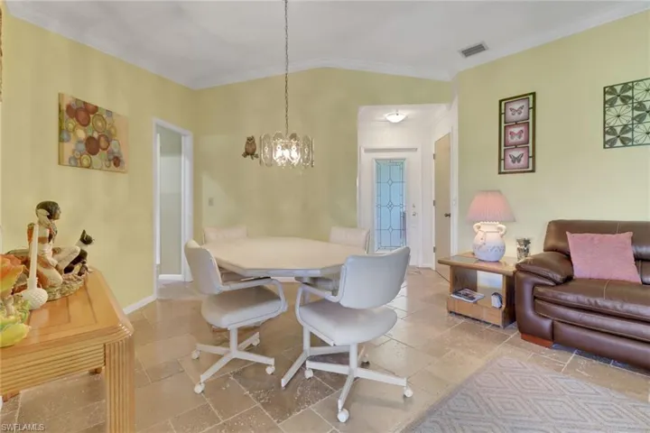 Dining room with crown molding, a chandelier, and stone tile flooring